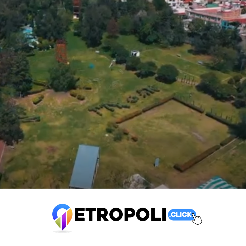 La imagen muestra una vista aérea de la zona del Parque Naucalli antes de la instalación de Tierra Jurásica. En ella se aprecia un espacio con amplias superficies de pasto, árboles, arbustos y elementos de jardinería que formaban parte del paisaje del parque.